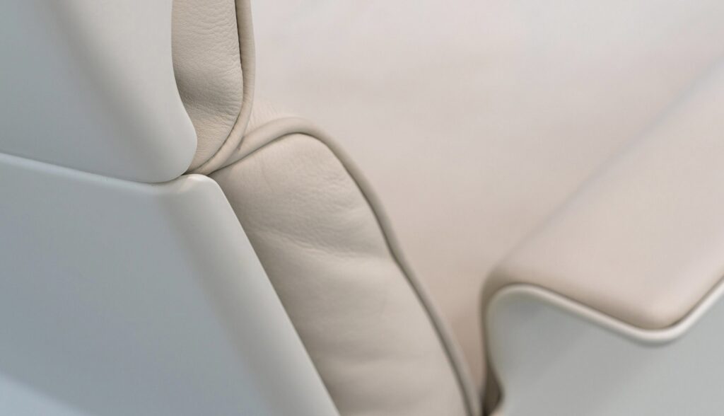 비초에 620 체어의 상단 모서리 부분으로, 가죽 쿠션과 외부 쉘이 정교하게 맞물린 클로즈업 샷