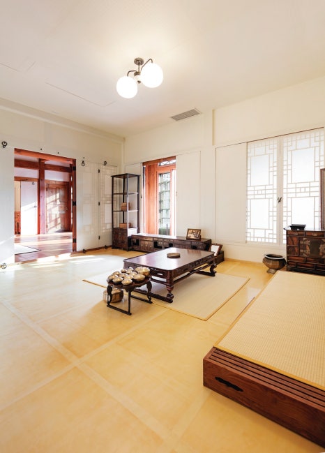 서울 북촌 백인제 가옥의 안방 내부. 은은한 채광이 드는 방 안에는 전통 목재 평상과 유기그릇이 놓인 소반이 배치되어 있다. 특히 미닫이문 너머로 마루와 다른 방이 복도로 길게 이어지는 구조가 보여, 이동의 편의성을 고려한 근대 한옥의 특징적인 평면 구성을 확인할 수 있다.