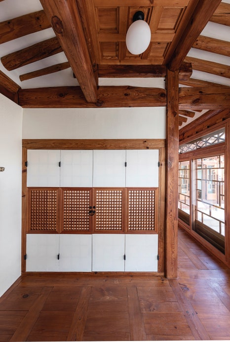 서울 북촌 백인제 가옥의 할머니방 내부 모습. 정면에는 흰색 창호지와 나무 격자무늬로 장식된 깔끔한 붙박이장(벽장)이 설치되어 있어 공간 활용의 효율성을 보여준다. 천장의 둥근 근대식 조명과 우측으로 연결되는 마루 복도는 전통 한옥에 도입된 현대적 생활 양식을 잘 나타낸다.