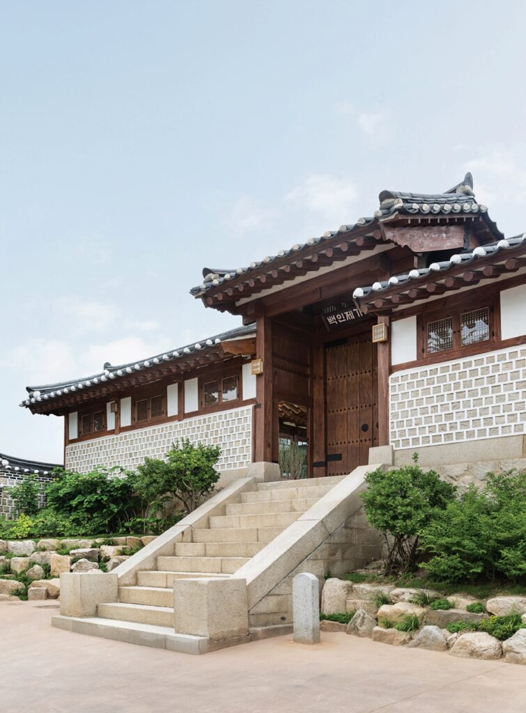 서울 북촌 백인제 가옥의 주 출입구인 솟을대문의 측면 모습. 권위를 상징하는 높은 전통 대문 옆으로, 근대 시기 건축 재료인 붉은 벽돌로 견고하게 쌓아 올린 높은 담장이 경사진 골목길을 따라 이어져 있다. 전통 양식과 근대 재료가 혼재된 일제강점기 최상류층 가옥의 특징을 보여준다.