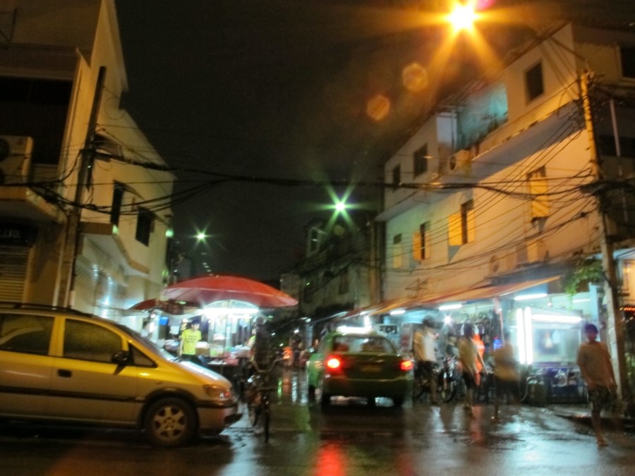 어두운 밤, 밝은 전등이 켜진 노점상들과 지나가는 자동차들이 만들어내는 방콕 거리의 야경