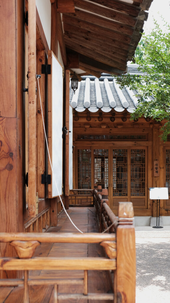 전통 한옥의 나무 기둥과 정갈한 창호, 기와지붕이 겹쳐 보이는 부암동 무계원의 고즈넉한 복도 풍경