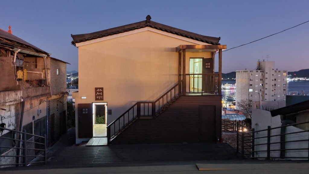 목포진 역사공원 인근에 위치한 '소년 김대중 공부방'의 저녁 풍경. 은은한 조명이 켜진 2층 건물 외벽에 '소년 김대중 공부방'이라는 현판이 걸려 있다. 건물 너머로 목포 항구의 바다와 도심 야경이 배경으로 펼쳐져 있어, 한국 현대사의 거목이 꿈을 키웠던 장소의 고즈넉하고 낭만적인 분위기를 자아낸다.