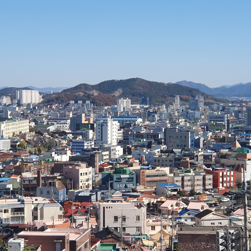 유달산 자락에서 내려다본 목포 원도심의 시가지 전경. 다닥다닥 붙은 낮은 주택들과 근대 건축물들이 빽빽하게 밀집해 있고, 그 뒤로 나지막한 산세가 도시를 감싸고 있다. 화려함 대신 세월의 흔적이 묻어나는 이 풍경은 '지붕 없는 박물관'이라 불리는 목포의 역사적 깊이와 서민들의 삶의 터전을 있는 그대로 보여준다.
