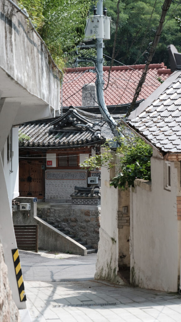 현대식 전신주와 전통 한옥의 기와지붕이 공존하는 부암동의 좁고 가파른 오르막 골목길 전경