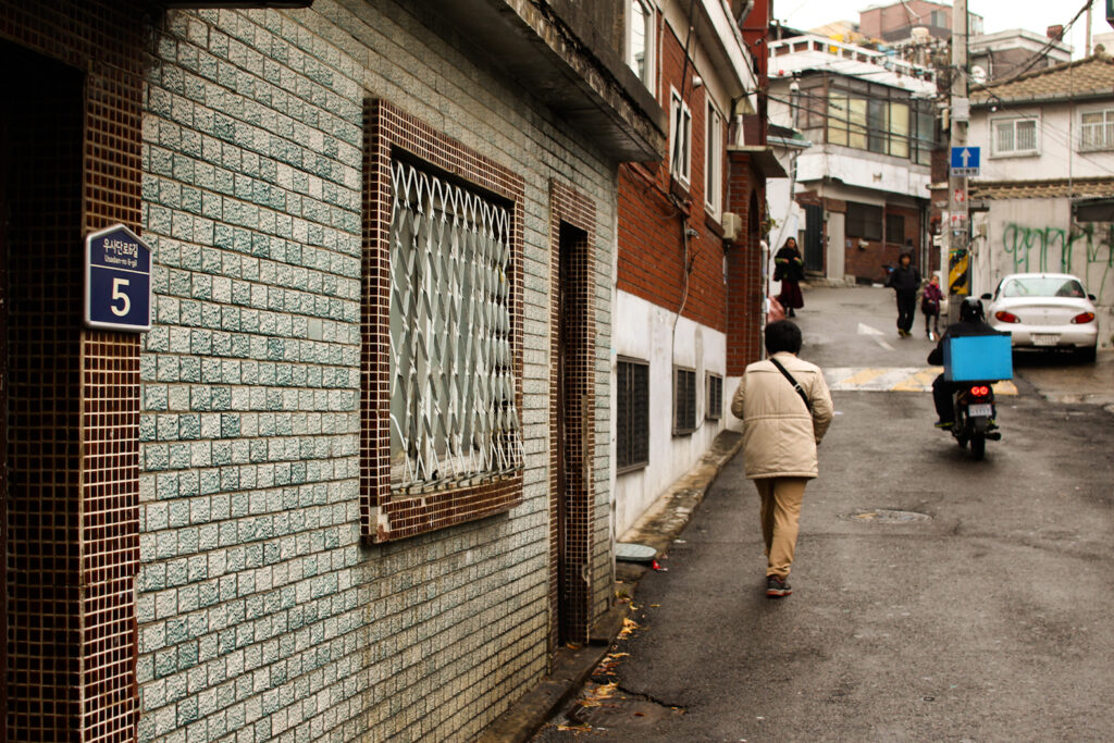 모자이크 타일 벽이 있는 우사단로 10길 골목과 길을 걷는 보행자들